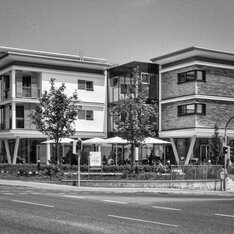 Espachstift: mehrgeschossiger Neubau mit Vordach und Außenbestuhlung an der Straße, Schwarzweißaufnahme