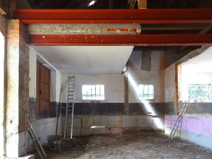 Derselbe Raum vor der Sanierung: Rohbau mit Stahlträgern und Leiter