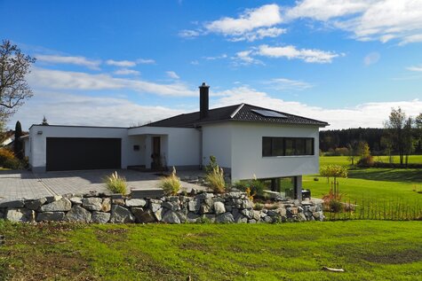 Haus SMS von der Straßenseite mit Garage und Natursteinböschung