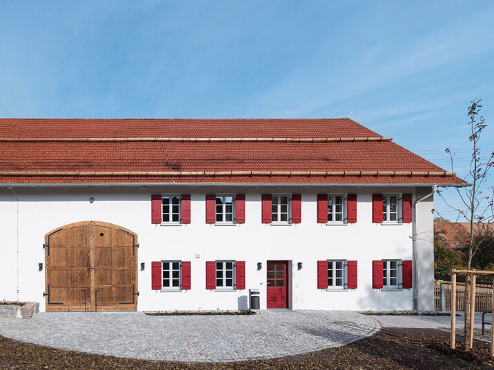 Hofseite nach der Sanierung mit neuem Holztor und gepflastertem Vorplatz